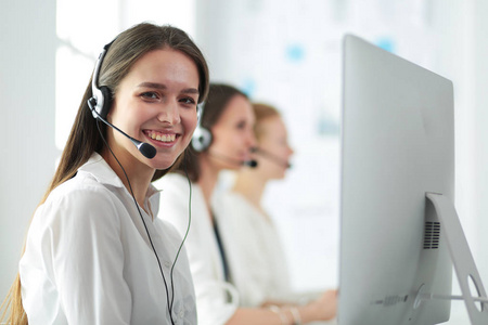 微笑的商人或热线电话操作员与耳机和计算机在办公室