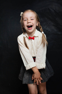 快乐的孩子女孩在校服有乐趣和笑在粉笔板的背景。回到学校销售理念