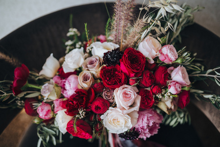 婚礼。胸花。粮食。图稿。一束红色的花，粉红色的花朵和绿叶与丝带是在黑色的椅子上