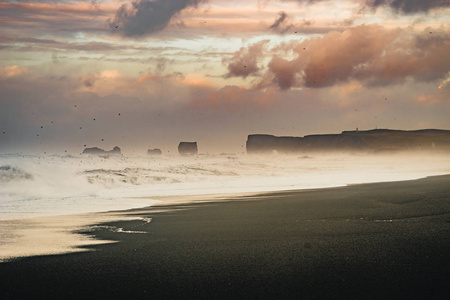 在冰岛著名的黑色沙滩 Reynisfjara 日出。刮风的早晨。海浪。五彩缤纷的天空。早晨日落