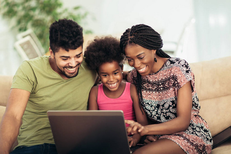 非洲裔美国人家庭使用笔记本电脑在起居室
