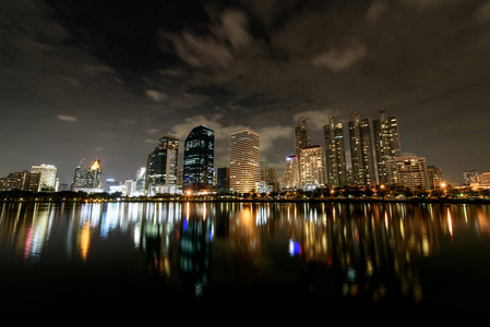 夜空的全景景观, 云流过现代建筑的 Benchakitti 公园与灯光反射在夜间城市。城市景观摄影, 现代夜景, 灯光反射, 曼