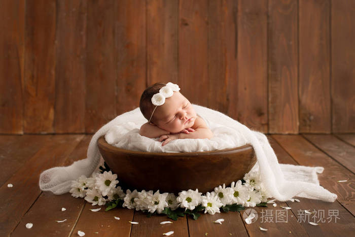在棕色背景的新生女孩与菊花花.拍摄为新生儿准备的.从出生起7天.