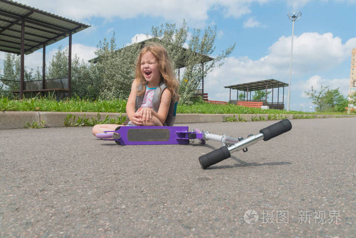 一个女孩, 一个孩子从滑板车上掉下来, 伤了膝盖, 痛苦地尖叫着.