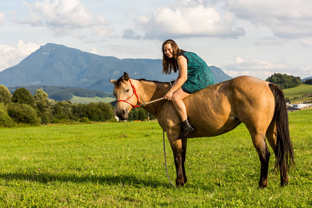 女孩穿着绿色的坐在斯洛伐克匹棕色的马照片