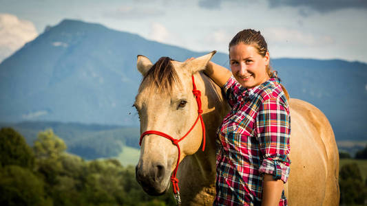 与一匹马在斯洛伐克的蓝色和红色的映射衬衫的女孩