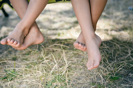 特写坐在绿草的赤脚女腿女赤脚腿可爱的身材匀称的小女孩赤脚站在全身
