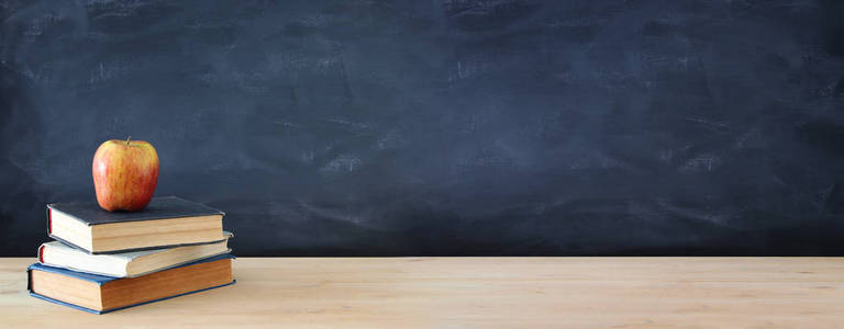 回到学校的概念。黑板前木桌上的书和苹果栈