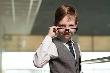 男孩在一个企业身着眼镜, 站在办公室, 与文件