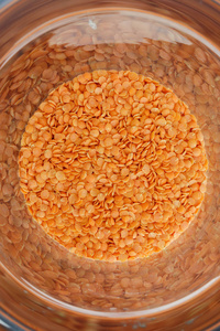 储罐中的红扁豆.明亮的红色背景的谷物照片