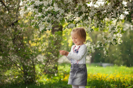 可爱的女孩在一个盛开的苹果果园在阳光明媚的春天天