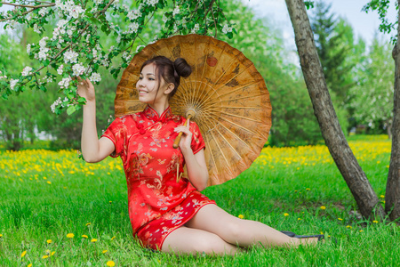 在传统的中国红美丽亚洲女孩打扮与竹伞