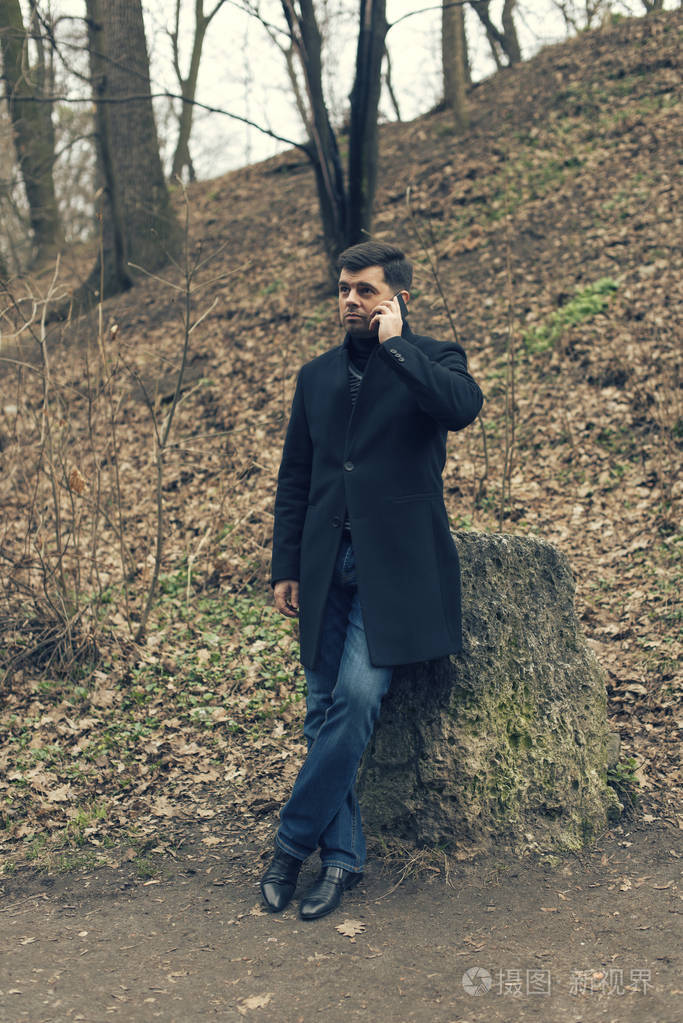 一名男子在一件外套走在春天公园里