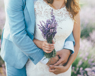 新婚夫妇拥抱在薰衣草领域与花束