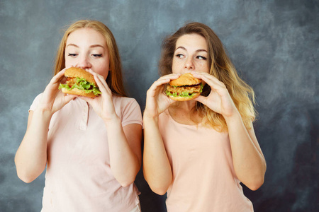 两个可爱的年轻女人吃美味的汉堡