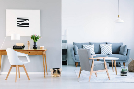 白色椅子在木桌与花在客厅内部与海报和沙发。真实照片