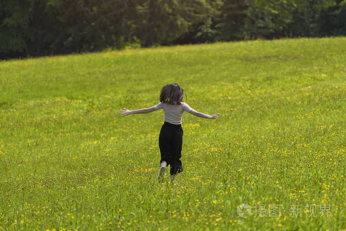 带花束的女孩正在花草地上奔跑.阳光明媚的夏日