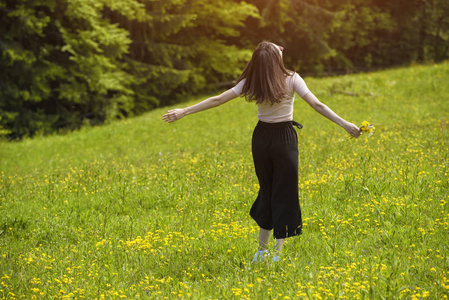 带着花束的微笑的年轻女人正在花丛中打转。夏日