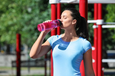 户外运动的年轻女人喝水