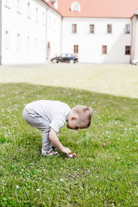 有石头的孩子。这个男孩正在那座历史性的建筑周围玩耍。在教堂附近的院子里。小男孩