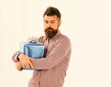 穿格子衬衫的家伙拥抱礼物盒。带蓝色礼品和白色弓的男子气概