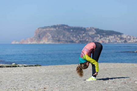 健康和健身的生活方式少妇在海滩上伸展