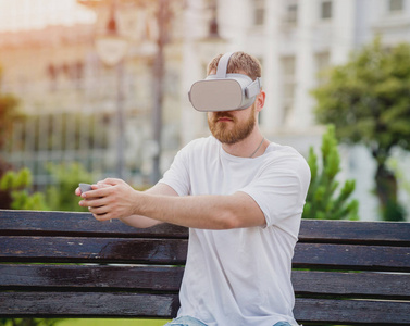 年轻的金发胡子男子玩游戏戴着虚拟现实眼镜在街上。Vr 耳机