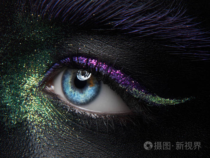 宏观和特写创意化妆主题: 美丽的女性眼睛与黑色皮肤绿色和紫色的颜料