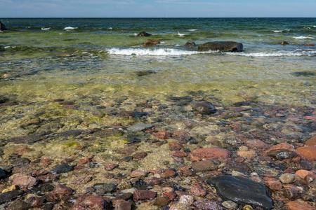 岩石海海滩以宽广的角度透视在海与晴朗的天空和波浪