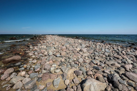岩石海海滩以宽广的角度透视在海与晴朗的天空和波浪