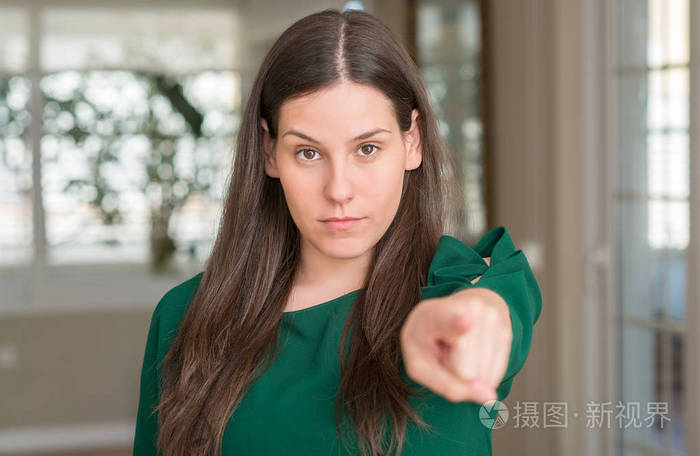 年轻漂亮的女人在家里用手指指着相机和你, 手牌, 正面和自信的手势从