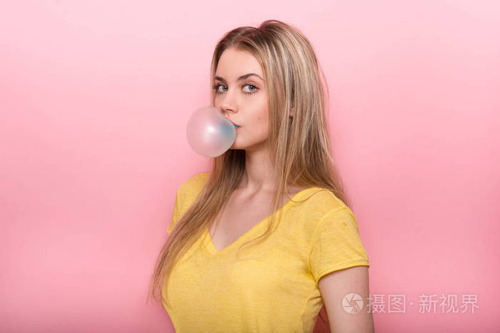 可爱的小女孩吹蓝色泡泡糖粉红墙附近