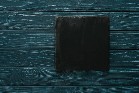 绿色木桌上黑色石材切割板的顶部视图