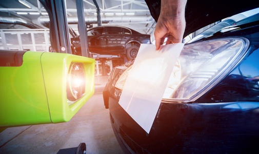 工人检查和调整汽车照明系统的车头灯。汽车维修服务