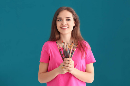 美丽的女性艺术家与套画笔的颜色背景