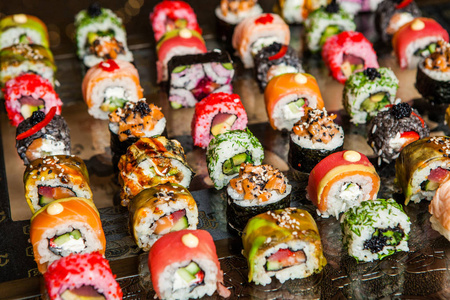 不同的寿司食物种类送达黑色背景。美味的新鲜寿司卷与鱼和米饭在板上的特写。在一家餐厅的木盘子寿司卷送达
