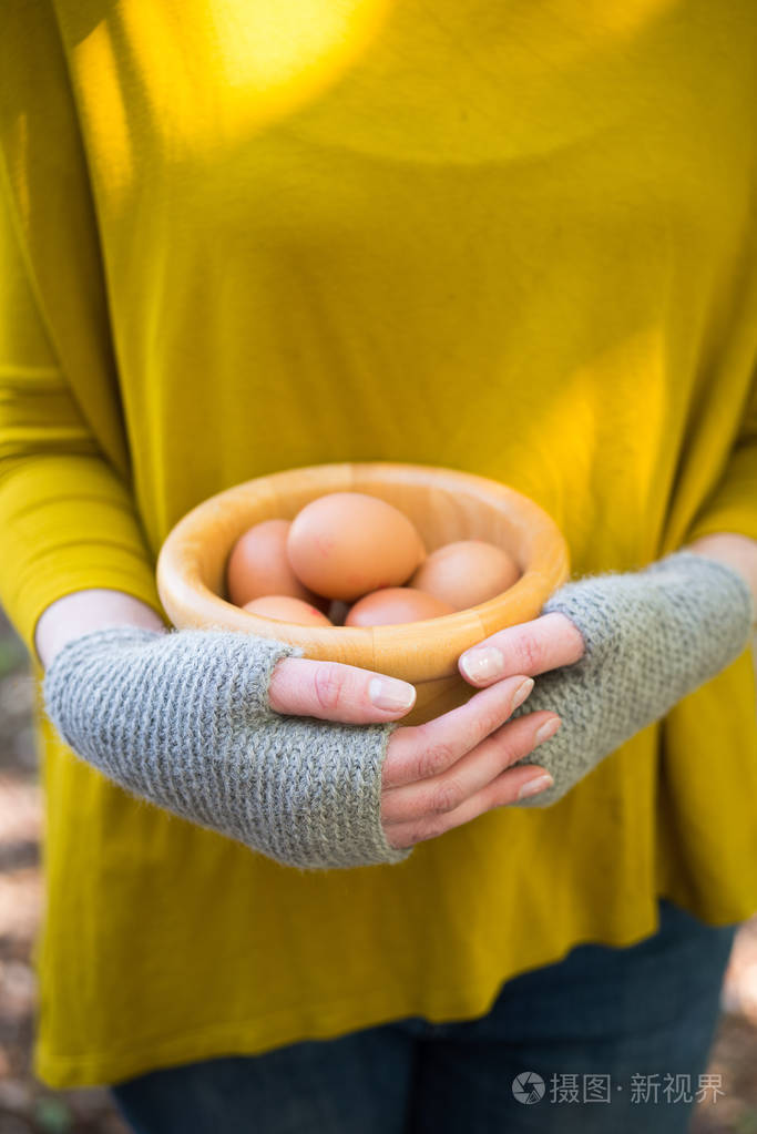 手在毛线手套拿着碗里的鸡蛋