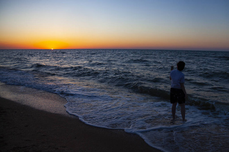 少年用行动照相机日落的海