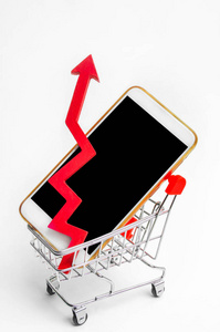 手机在超市的手推车和红色的箭头向上。对购买智能手机的需求很高。网上商店。消费信贷。孤立的白色背景