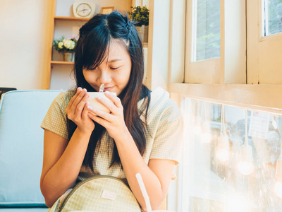 女人坐在沙发上喝着杯拿铁咖啡