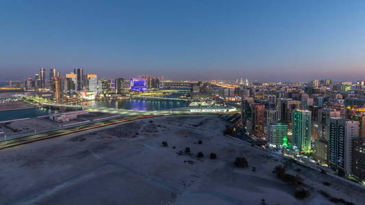 阿布扎比市中心的空中天际线从前一天到晚上过渡 timelapse 日落后与照明摩天大楼