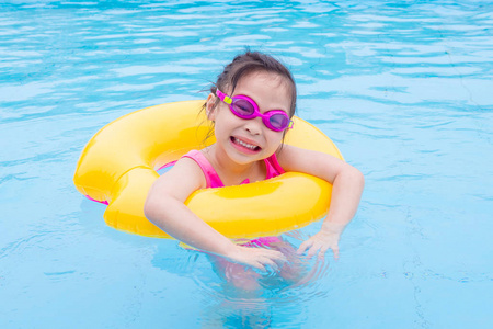 小亚洲女孩游泳与圆环在水池
