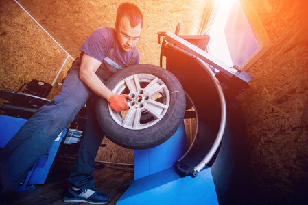 专业的汽车修理工在车轮上更换轮胎。汽车维修服务。汽车车轮平衡