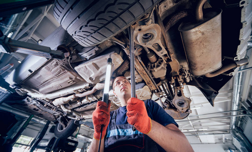 汽车修理工在维修服务站检查汽车吊架.背景照片