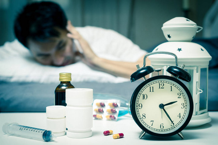 亚洲男人在床上与平板电脑和晚上痛苦的失眠，宿醉，头痛的药物