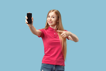 一个自信的休闲女孩的肖像显示空白屏幕手机在蓝色背景下隔离