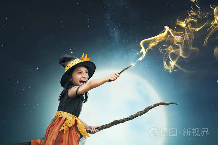 美丽的亚洲巫婆女孩使用魔术棒与夜背景