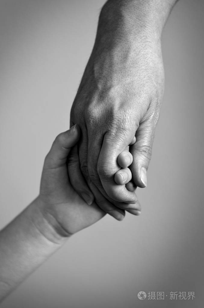 成人牵着的孩子的家庭爱的手