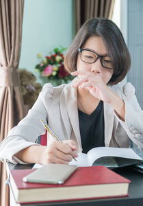 年轻女孩的短发在智能休闲穿着笔记本电脑, 而坐在窗口附近的家庭办公室