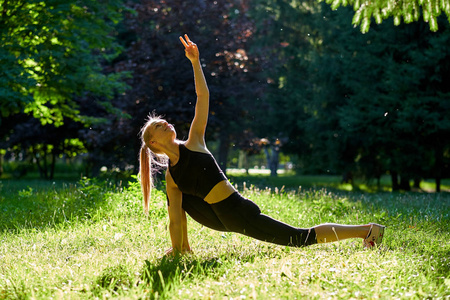 瑜伽。在公园里练习瑜伽或跳舞或伸展自然的年轻女子。健康生活方式概念